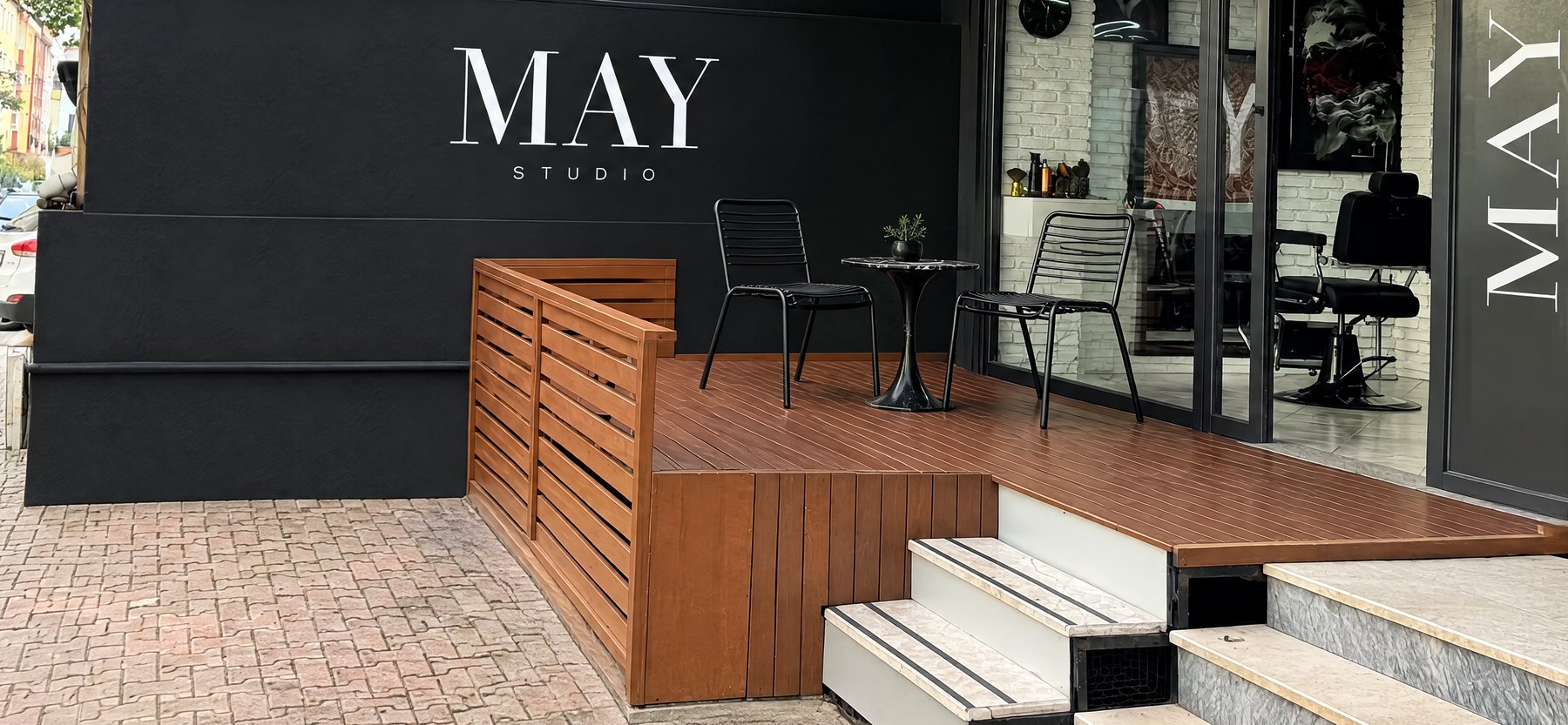MAY Studio dış cephesi: siyah duvarda MAY yazısı, ahşap teras ve cam kapı